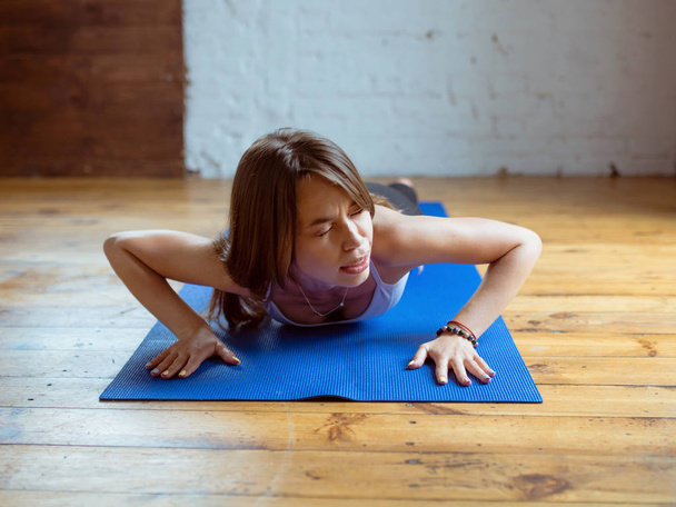 giovane donna in forma in abbigliamento sportivo iniziare lo yoga e hanno problemi con asana yoga al coperto. Yoga e sport concetto
 - Foto, immagini