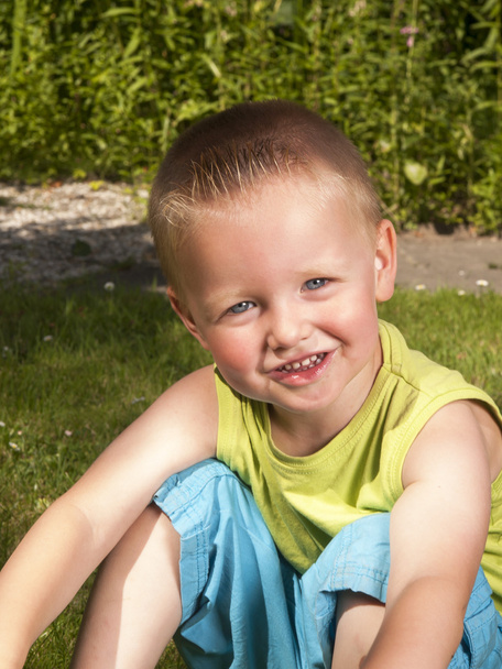 Kleinkind lacht auf dem Rasen im Garten - Foto, Bild