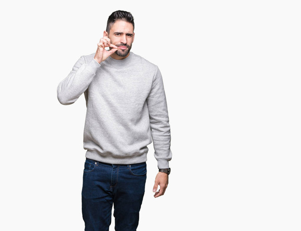Young handsome man wearing sweatshirt over isolated background mouth and lips shut as zip with fingers. Secret and silent, taboo talking - Photo, Image