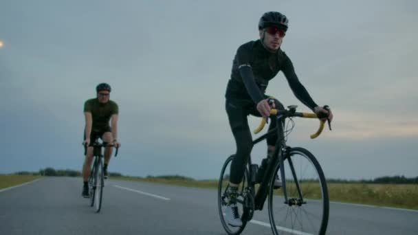 朝は一緒に彼のガール フレンド、両方身に着けているヘルメット彼のレース自転車に乗る男性のプロのサイクリストにひげを生やしたハンサムと眼鏡、太陽の間に輝いています。. - 映像、動画