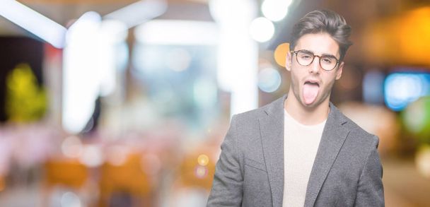 若いビジネス人が舌を付着分離の背景に眼鏡をかけて出て面白い表現に満足。感情の概念. - 写真・画像