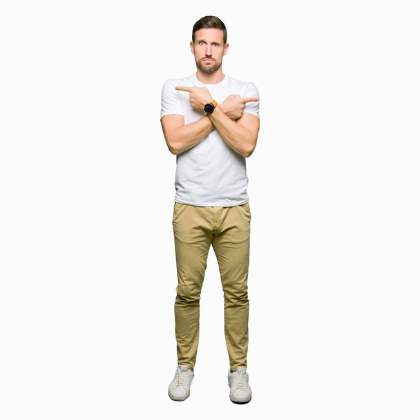 Komea mies yllään rento valkoinen t-paita Osoittaa molemmin puolin sormin, eri suuntaan eri mieltä
 - Valokuva, kuva