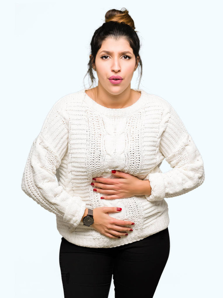 Young beautiful woman wearing winter sweater with hand on stomach because nausea, painful disease feeling unwell. Ache concept. - Foto, Imagem