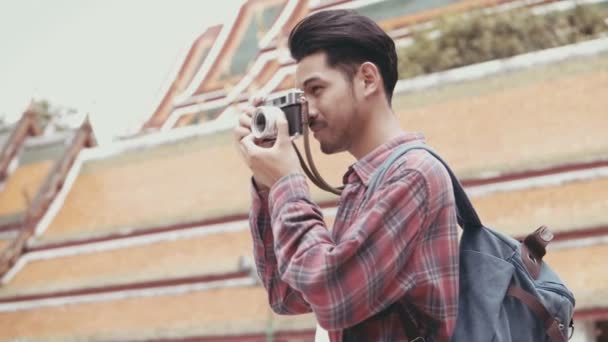 Vonzó fiatal ázsiai férfi turisták séta és a film kamera fotózás a templomban Thaiföld. Ázsiai férfi blogger boldog élvezi szabadidős életmód utazás. - Felvétel, videó