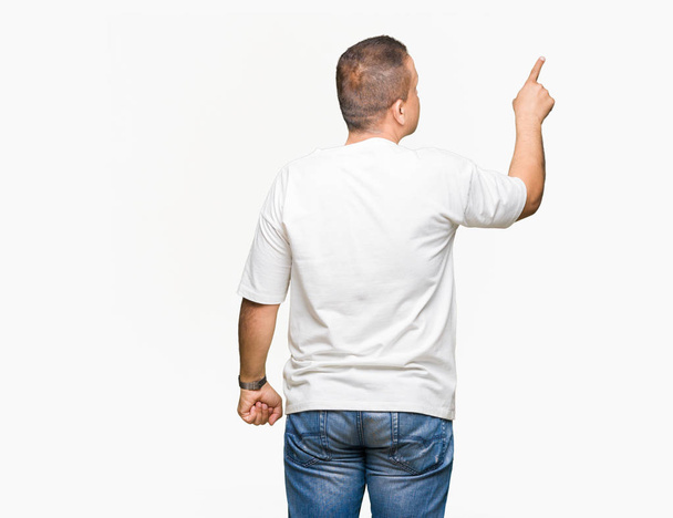 Wearig arab muž středního věku bílé tričko přes izolované pozadí vystupují dozadu směřující za prstů rukou - Fotografie, Obrázek