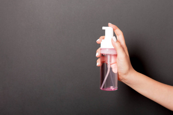 Femmina mano tenuta spray crema bottiglia di lozione isolato. Ragazza dare prodotti cosmetici su sfondo bianco
 - Foto, immagini