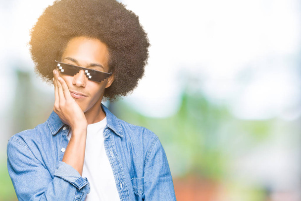 Joven afroamericano con cabello afro usando gafas de vida de matón pensando que se ve cansado y aburrido con problemas de depresión con los brazos cruzados
. - Foto, imagen