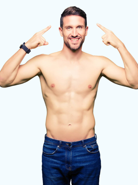 Handsome shirtless man showing nude chest Smiling pointing to head with both hands finger, great idea or thought, good memory - Foto, immagini