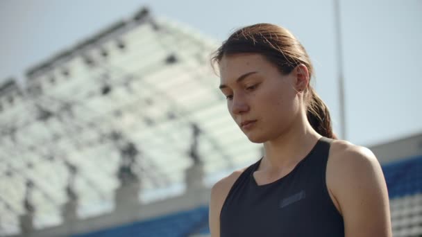 Beautiful woman athlete at the stadium breathing and preparing to start the race. Motivation and tuning for the race. Concentration and attitude. - Video, Çekim
