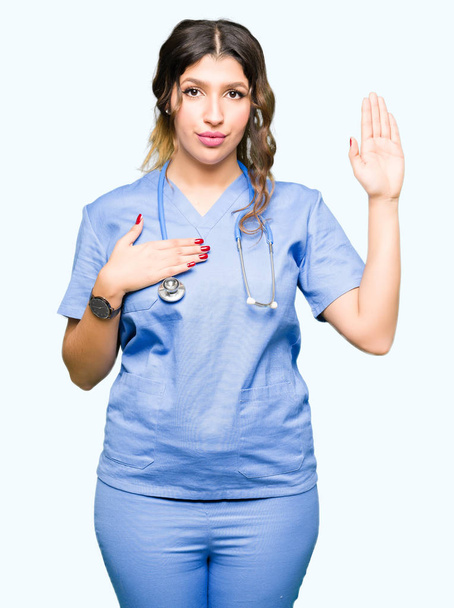 Взрослая женщина-врач в медицинской форме, ругаясь рукой на груди и открытой ладони, дает клятву верности
 - Фото, изображение