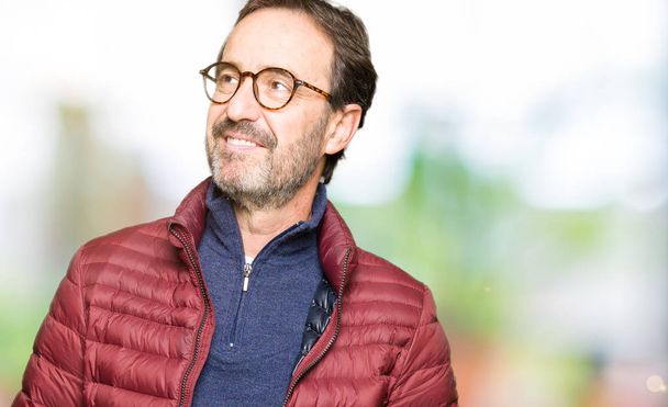 Middle age handsome man wearing glasses and winter coat smiling looking side and staring away thinking. - Fotoğraf, Görsel