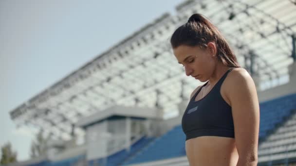Lassú mozgás: sportoló nő várja a kiindulási blokk futó pályán. - Felvétel, videó