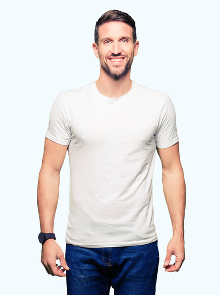Handsome man wearing casual white t-shirt with a happy and cool smile on face. Lucky person. - Foto, immagini