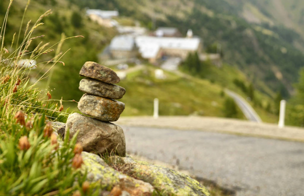 Stones stacked as a Zen memorial along a mountain road, a township in the background blurred and indistinguishable. - Photo, Image