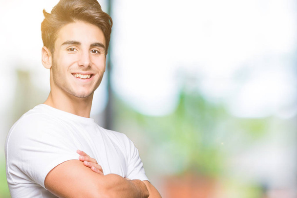 Young handsome man wearing white t-shirt over isolated background happy face smiling with crossed arms looking at the camera. Positive person. - Photo, Image