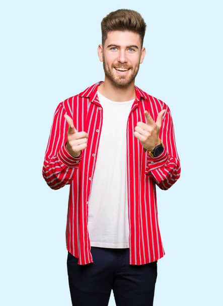 Genç yakışıklı kamera ile mutlu ve komik yüz için parmakları işaret giyen kırmızı gömlek adam. İyi enerji ve vibes. - Fotoğraf, Görsel