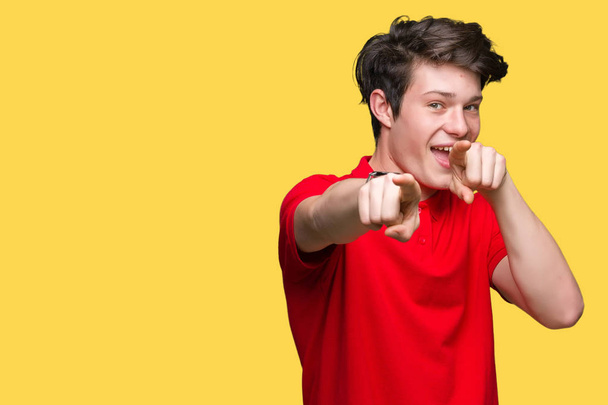 Молодой красивый мужчина в красной футболке на изолированном фоне указывает на тебя и камеру пальцами, улыбаясь позитивно и весело
 - Фото, изображение