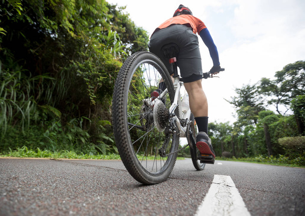 Woman cyclist riding mountain bike on tropical rainforest trail - Valokuva, kuva