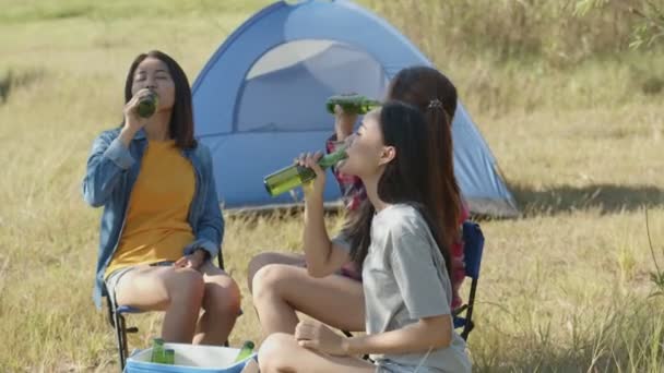 スローモーション:友達と自然を楽しみながらビールとクリンクグラスを飲みながらキャンプをしている若いアジア人女性のグループ. - 映像、動画