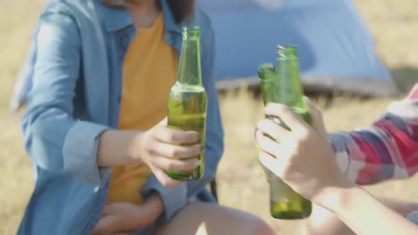 Nahaufnahme Portraitgruppe einer jungen Asiatin, die glücklich mit Freunden in der Natur campt und gemeinsam Bier trinkt und Gläser klirren lässt. - Filmmaterial, Video
