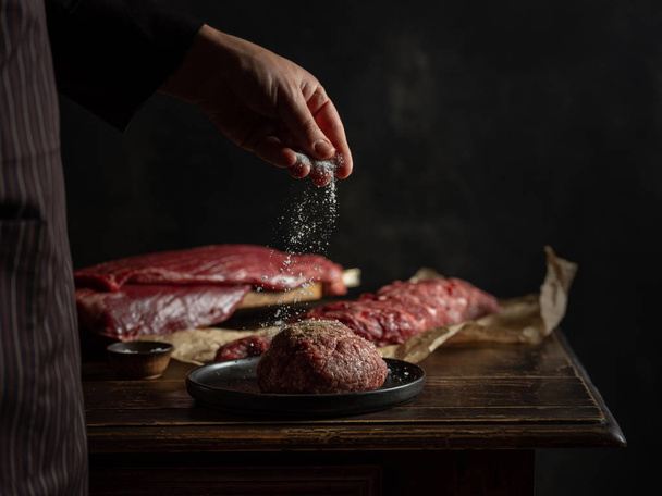 Chef preparing raw beef minced meat with spices and herbs - 写真・画像