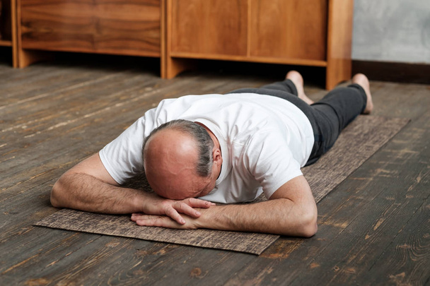 Homme âgé se reposant après l'exercice de yoga sur le sol. Sport à domicile pour la santé
. - Photo, image