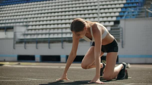 Slank jong meisje atleet is in staat om de begint te lopen in de pads op het spoor in slow motion. - Video