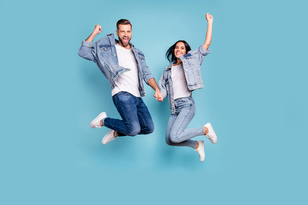 Photo of rejoicing overjoyed nice charming couple wearing jeans denim jackets enjoying their free time in summer while isolated with blue background - Foto, immagini