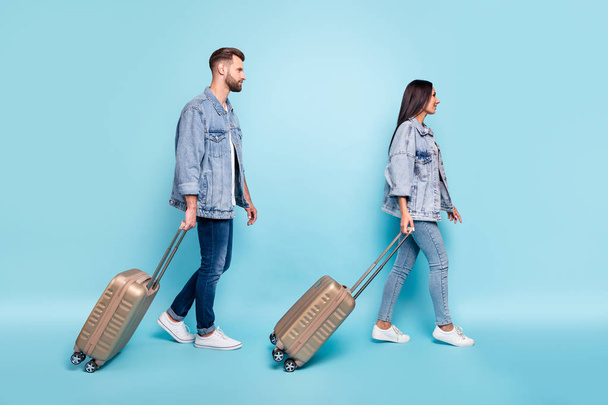 Full length profile side photo of lovely spouses holding trolley wearing denim jeans jackets isolated over blue background - Foto, Bild