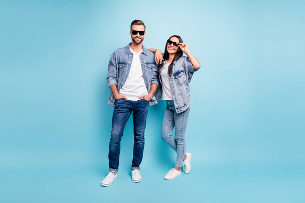Фотографія повного тіла красивого чоловіка і жінки з окулярами, посміхаючись у джинсовій куртці, ізольовані на синьому фоні
 - Фото, зображення