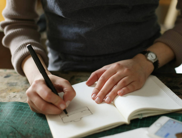 молодая брюнетка женщина пишет в ноутбук в швейной мастерской, ручной работы концепции - Фото, изображение