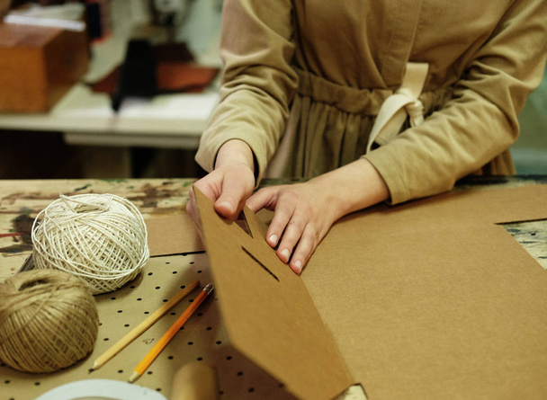 young brunette woman folds packing box in sewing workshop - Zdjęcie, obraz