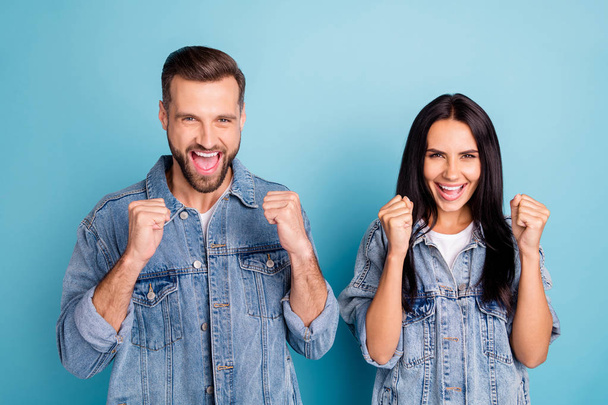 Portrait of charming spouses screaming yeah raising fists wearing denim jeans isolated over blue background - Fotoğraf, Görsel