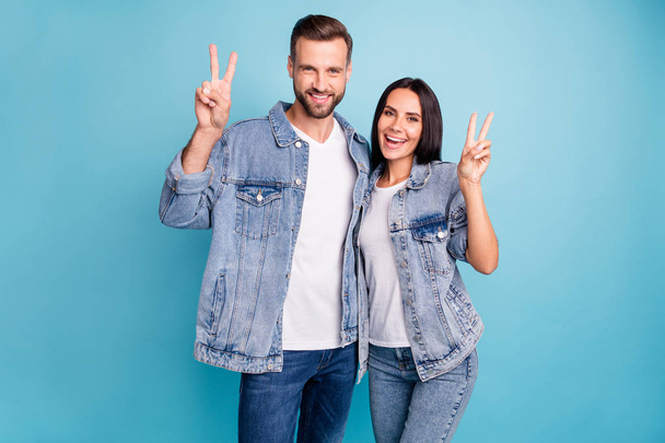 Portrait of cheerful married guy and girl making v-sign wearing denim jeans isolated over blue background - Foto, immagini
