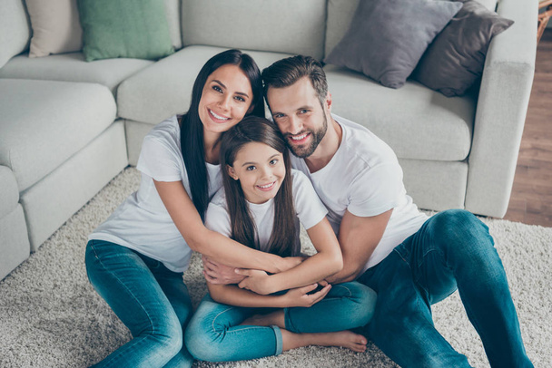 Portrait of nice attractive charming cute adorable idyllic careful cheerful cheery family wearing casual white t-shirts jeans denim mommy daddy cuddling at industrial loft style interior room house - Photo, Image