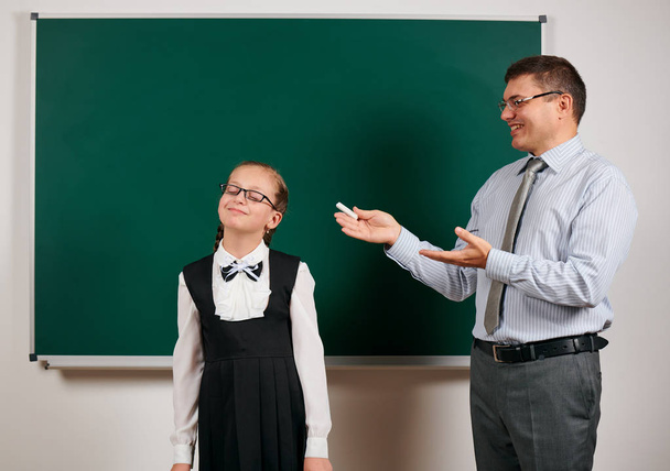 Portrait of a teacher and schoolgirl like as excellent pupil, posing at blackboard background - back to school and education concept - Photo, Image