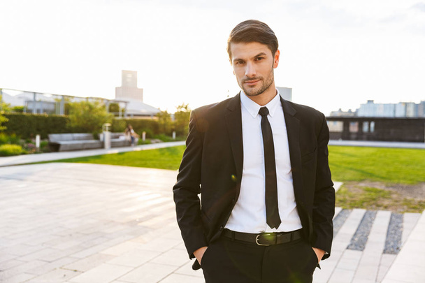 Handsome young businessman wearing suit walking outdoors - Фото, зображення
