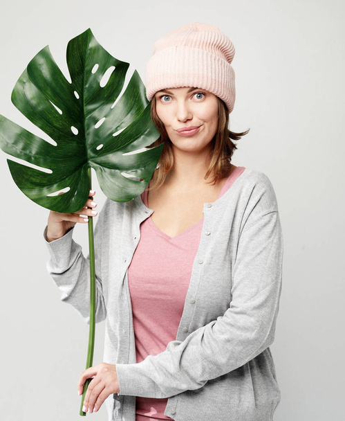 lifestyle and people concept - Beautiful young woman holding a leaf of a large tropical flower and smiling - Photo, Image