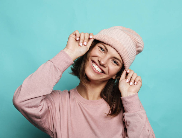 lifestyle and people concept - happy young emotional woman wearing pink hat and shirt over blue background - Foto, Bild