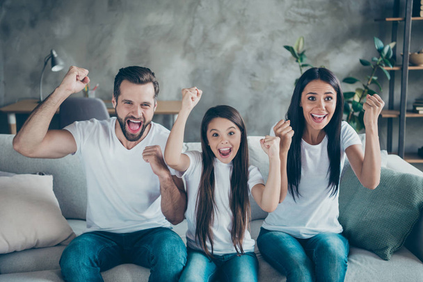 Portrait of nice attractive lovely charming cheerful cheery overjoyed family mommy daddy wearing casual white t-shirts sitting on divan having fun holiday indoors apartment - Foto, afbeelding