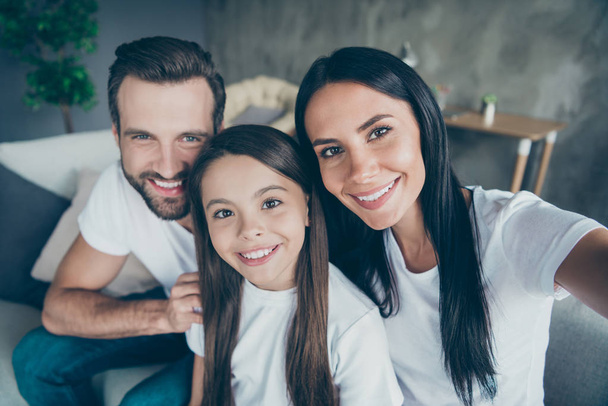 Self-portrait of nice attractive lovely sweet adorable charming cheerful cheery idyllic family mommy daddy wearing casual white t-shirts enjoying life holiday indoors apartment - Foto, imagen