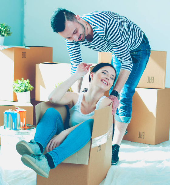 Onnellinen nuori pari purkamassa tai pakkaamassa laatikoita ja muuttamassa uuteen kotiin
 - Valokuva, kuva