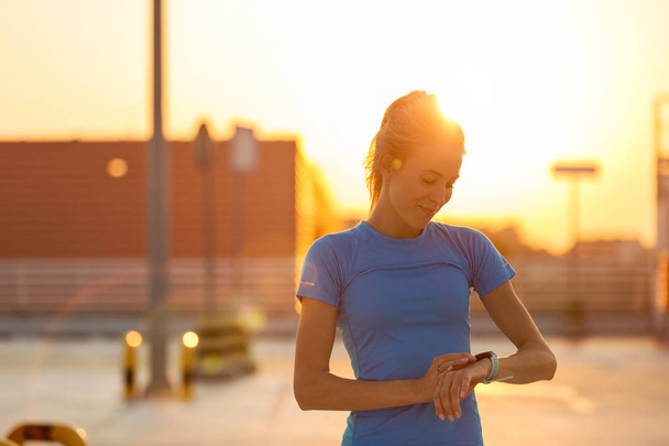 Young woman checking her smartwatch after exercising - Foto, afbeelding
