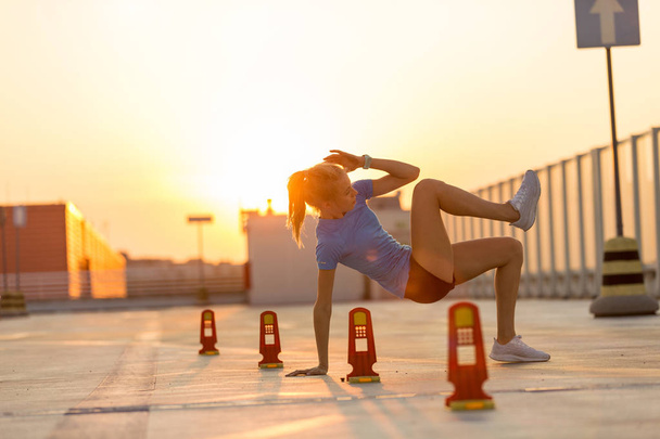 Νεαρή γυναίκα κάνει άσκηση γυμναστικής στην αστική περιοχή - Φωτογραφία, εικόνα