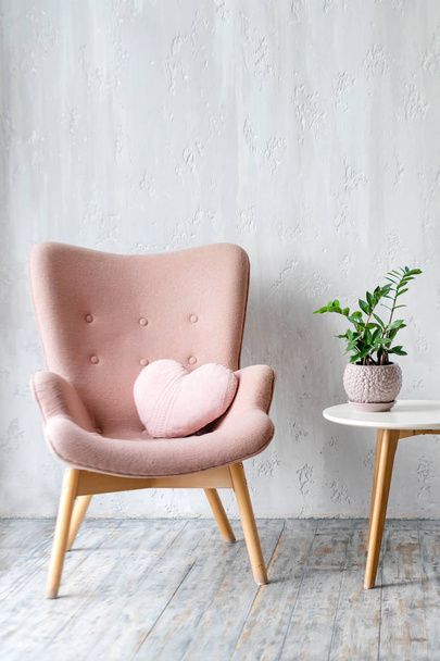 Stylowy różowy fotel z poduszką w kształcie serca w jasnym, minimalistycznym wnętrzu - Zdjęcie, obraz