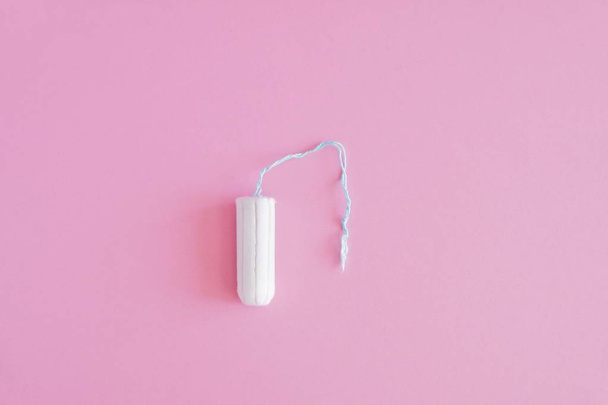 One hygienic tampon on a pink background. Menstrual mothly cycle, means of protection. Top view, flat lay, copy space for text. - Foto, Imagen