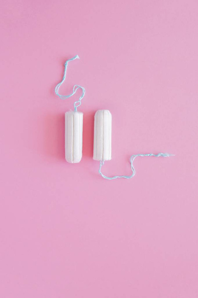 Two hygienic tampons on a pink background. Menstrual mothly cycle, means of protection. Top view, flat lay, copy space for text. - Photo, Image