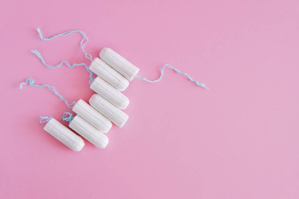 Several white sanitary tampons on a pink background. Menstrual mothly cycle, means of protection. Top view, flat lay, copy space for text. - Foto, Imagen