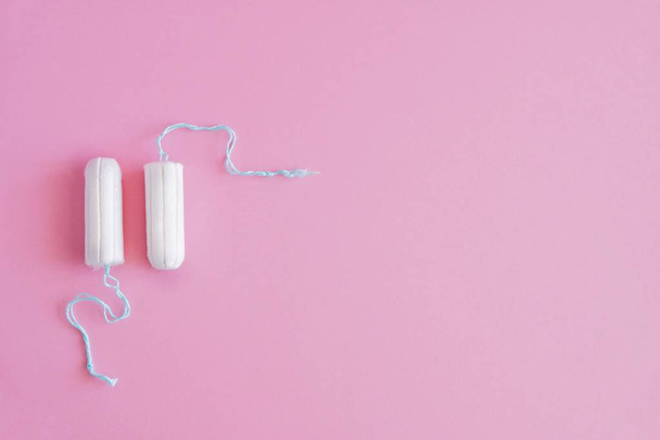 Two hygienic tampons on a pink background. Menstrual mothly cycle, means of protection. Top view, flat lay, copy space for text. - Photo, Image