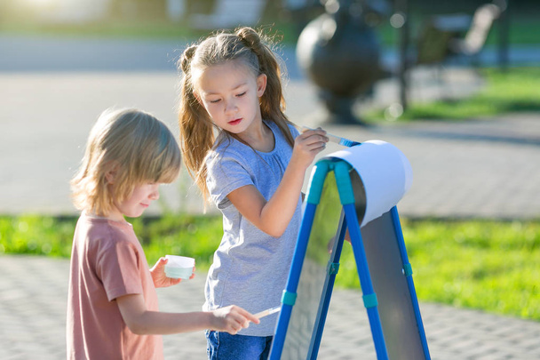 Children paint with paints on an easel in the park. - Photo, image